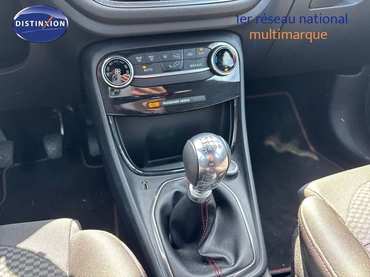Gros plan sur la console centrale du Ford Puma blanc 2022, mettant en valeur le levier de vitesse manuel et les commandes de climatisation.