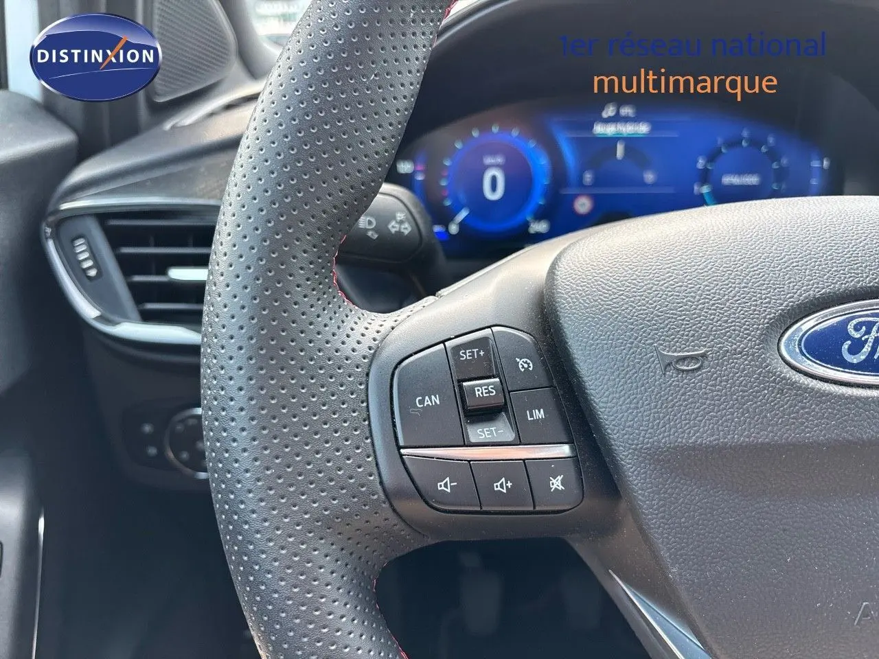 Gros plan sur le volant perforé et les commandes de régulateur du Ford Puma blanc, tableau de bord numérique en arrière-plan.