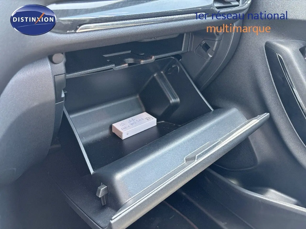 Gros plan sur la boîte à gants ouverte côté passager du Ford Puma blanc, montrant un petit objet posé à l'intérieur.