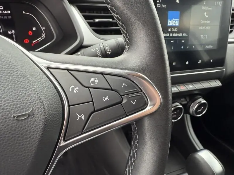 Gros plan sur les commandes au volant du Renault Captur E-Tech 145 Zen 2022, intérieur noir avec écran tactile visible.