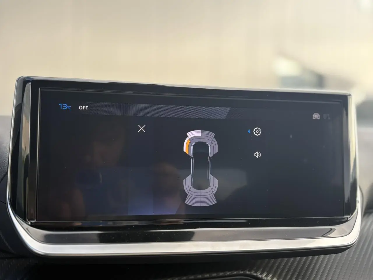Écran tactile du tableau de bord du Peugeot 2008 Hybrid 145, affichant l'aide au stationnement avec vue du véhicule en plan.