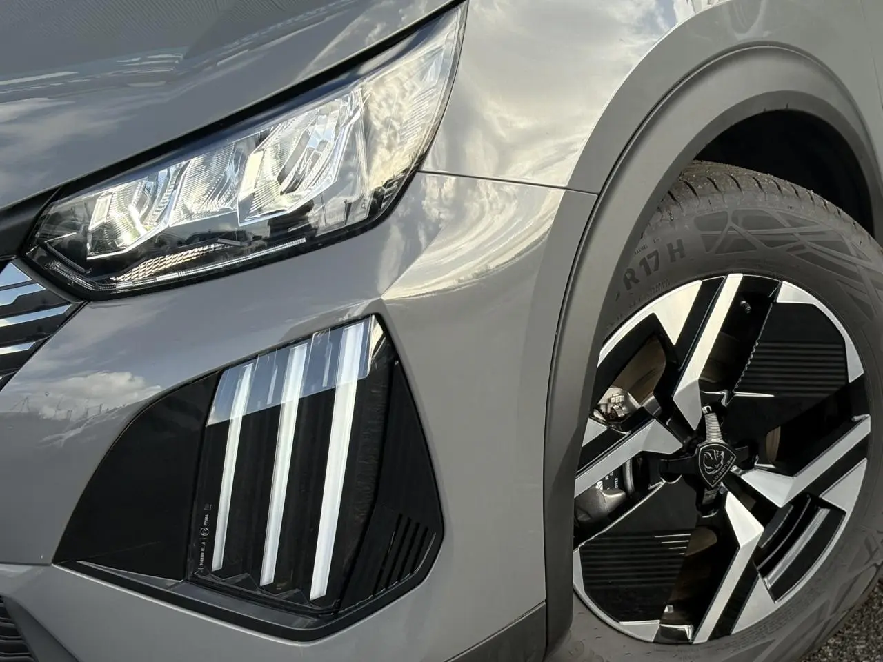 Gros plan sur l'avant droit gris Selenium du Peugeot 2008 Hybrid 145 avec feux LED 3 griffes et jante alliage 17 pouces.