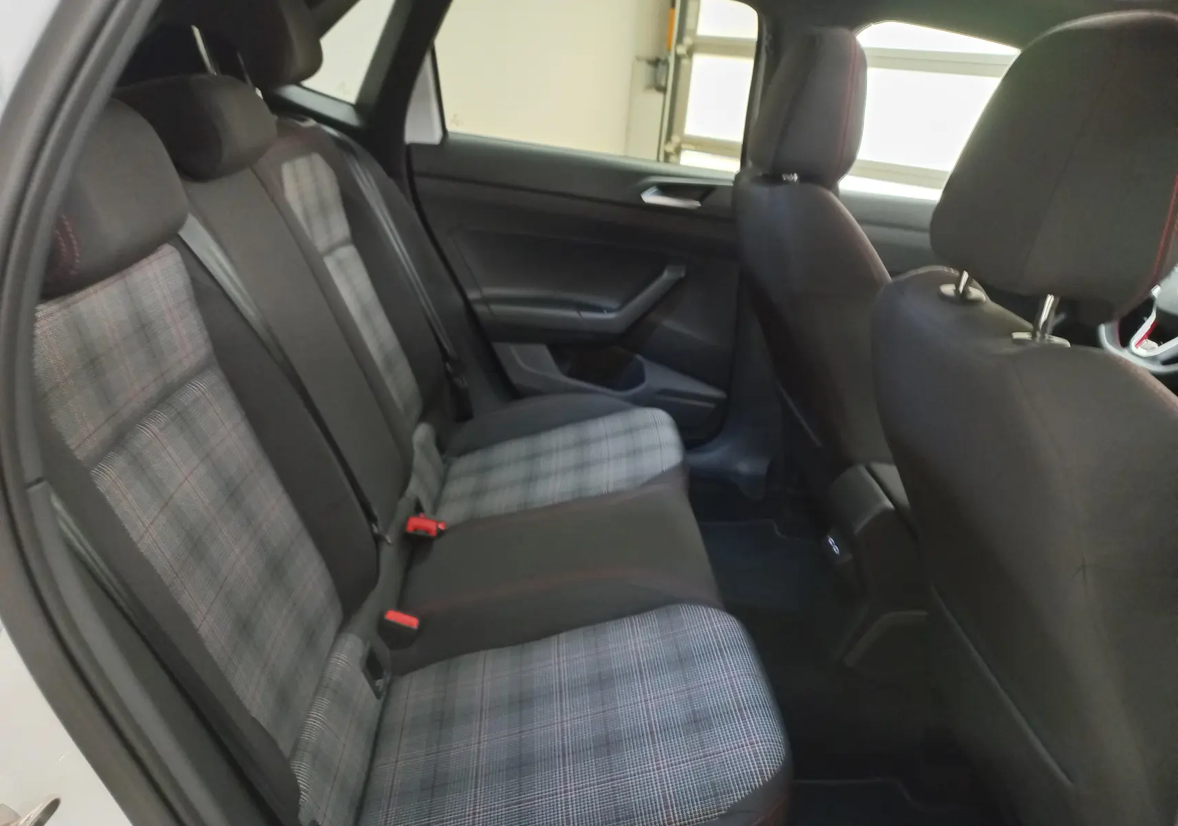 Vue intérieure arrière droite de la Volkswagen Polo 2024 avec sièges arrière en tissu à motif écossais gris et noir.