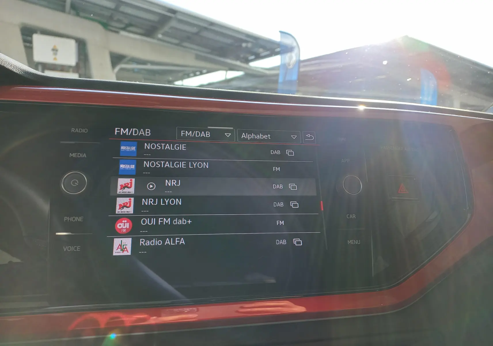 Écran tactile central de la Volkswagen Polo 2024 GTI, avec cadre rouge et affichage des stations radio FM/DAB.