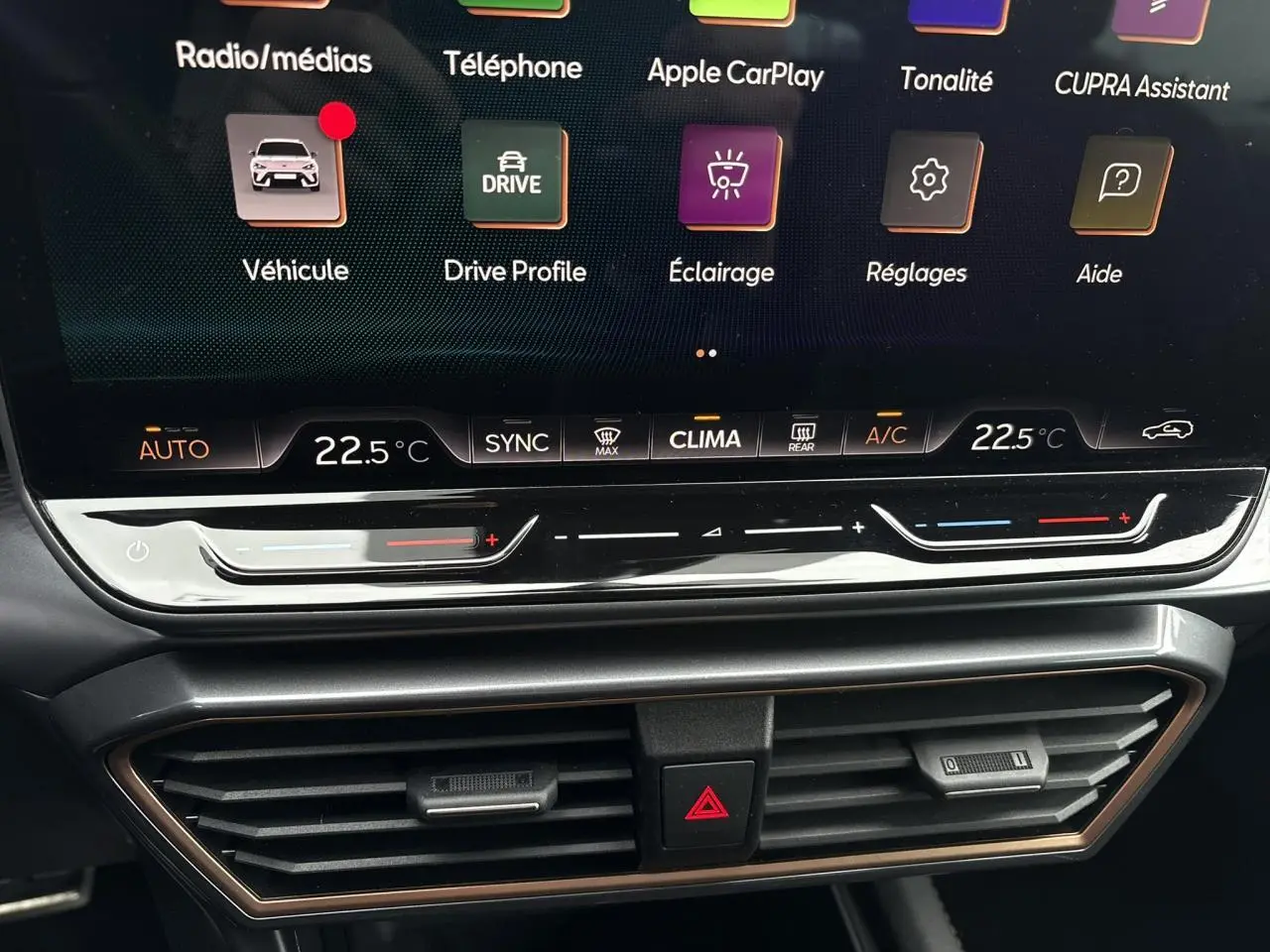 Gros plan sur l'écran tactile et la commande de climatisation du tableau de bord de la CUPRA Leon ST gris Graphene.