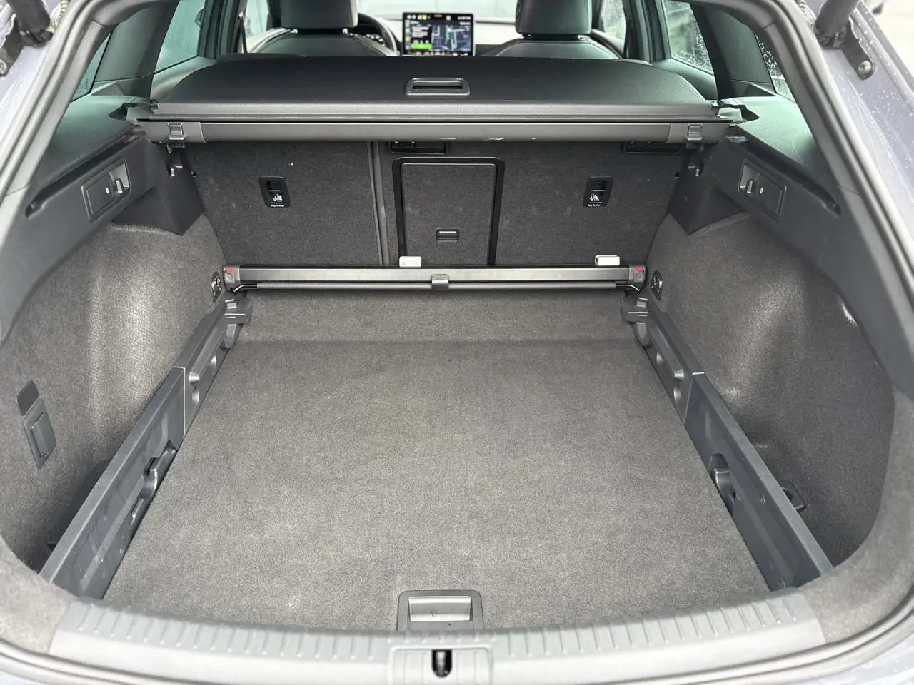 Vue intérieure du coffre spacieux de la CUPRA LEON ST 2025 en Gris Graphene, avec banquette arrière et tablette tactile visibles.