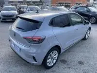 Vue arrière d'une Renault Clio V gris métal 2025, avec feux LED fins et lunette arrière teintée, sur parking extérieur.