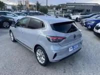 Vue 3/4 arrière droite d'une Renault Clio V gris métal 2025, version DCI 100 Evolution, stationnée en extérieur.