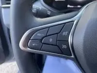 Vue intérieure centrée sur le volant de la Renault Clio V gris métal, avec tableau de bord numérique et écran tactile.