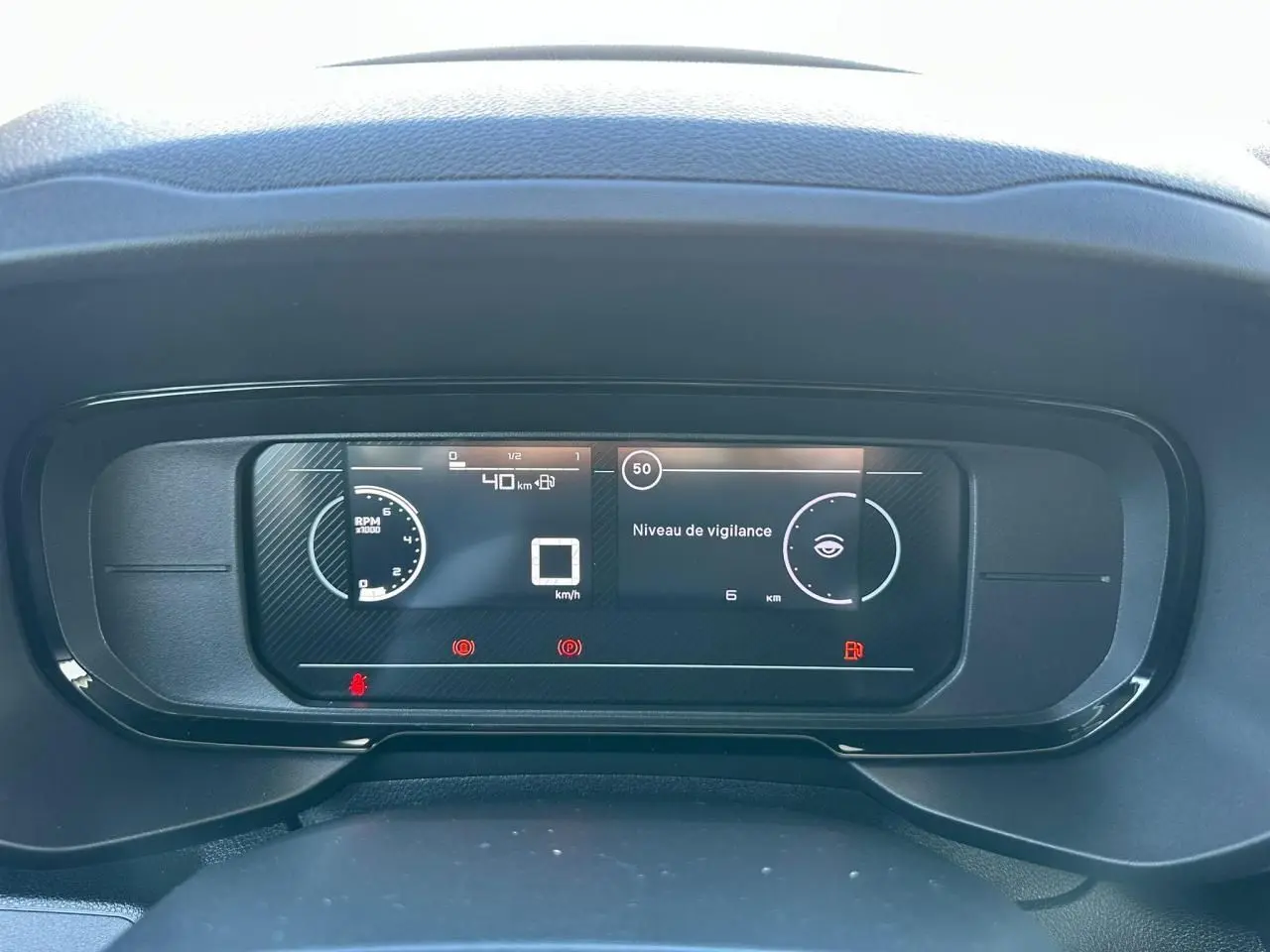 Vue rapprochée du tableau de bord numérique du Citroën Berlingo blanc, affichant la vitesse et le niveau de vigilance.