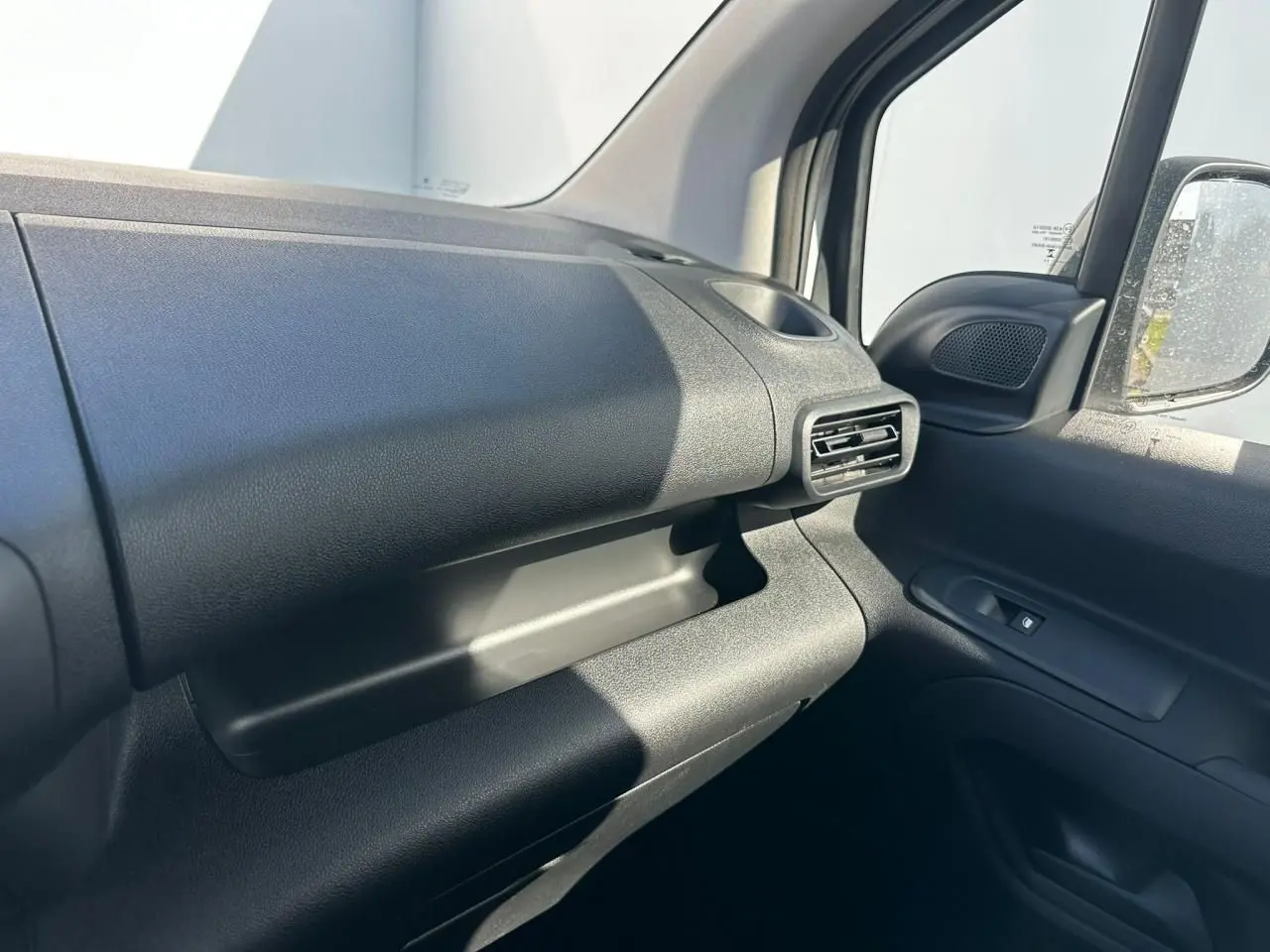 Détail de l’intérieur côté passager du Citroën Berlingo blanc, montrant la planche de bord et la grille d’aération.