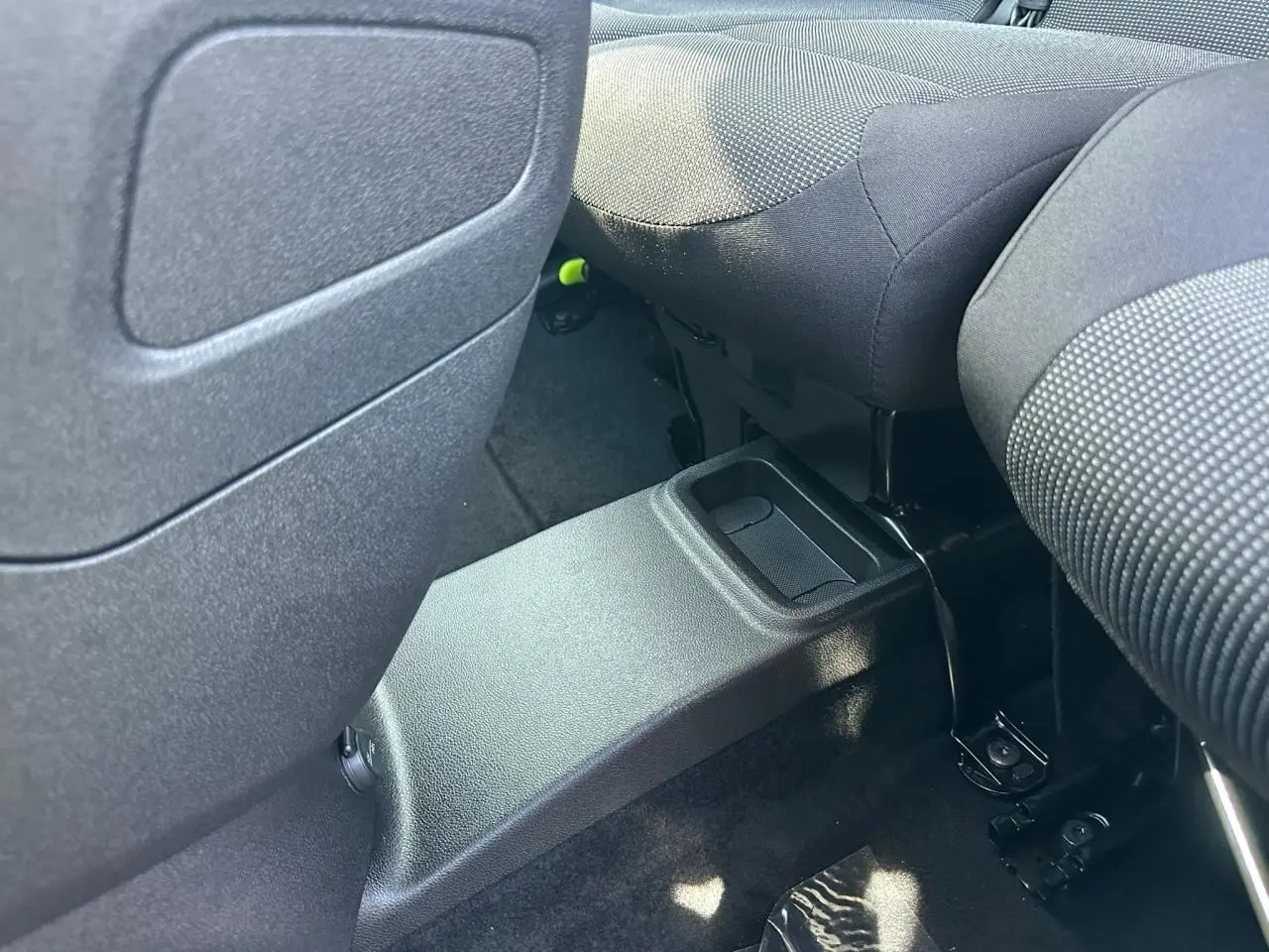 Vue rapprochée de l'espace entre les sièges arrière noirs du Citroën Berlingo III blanc, avec console centrale basse.