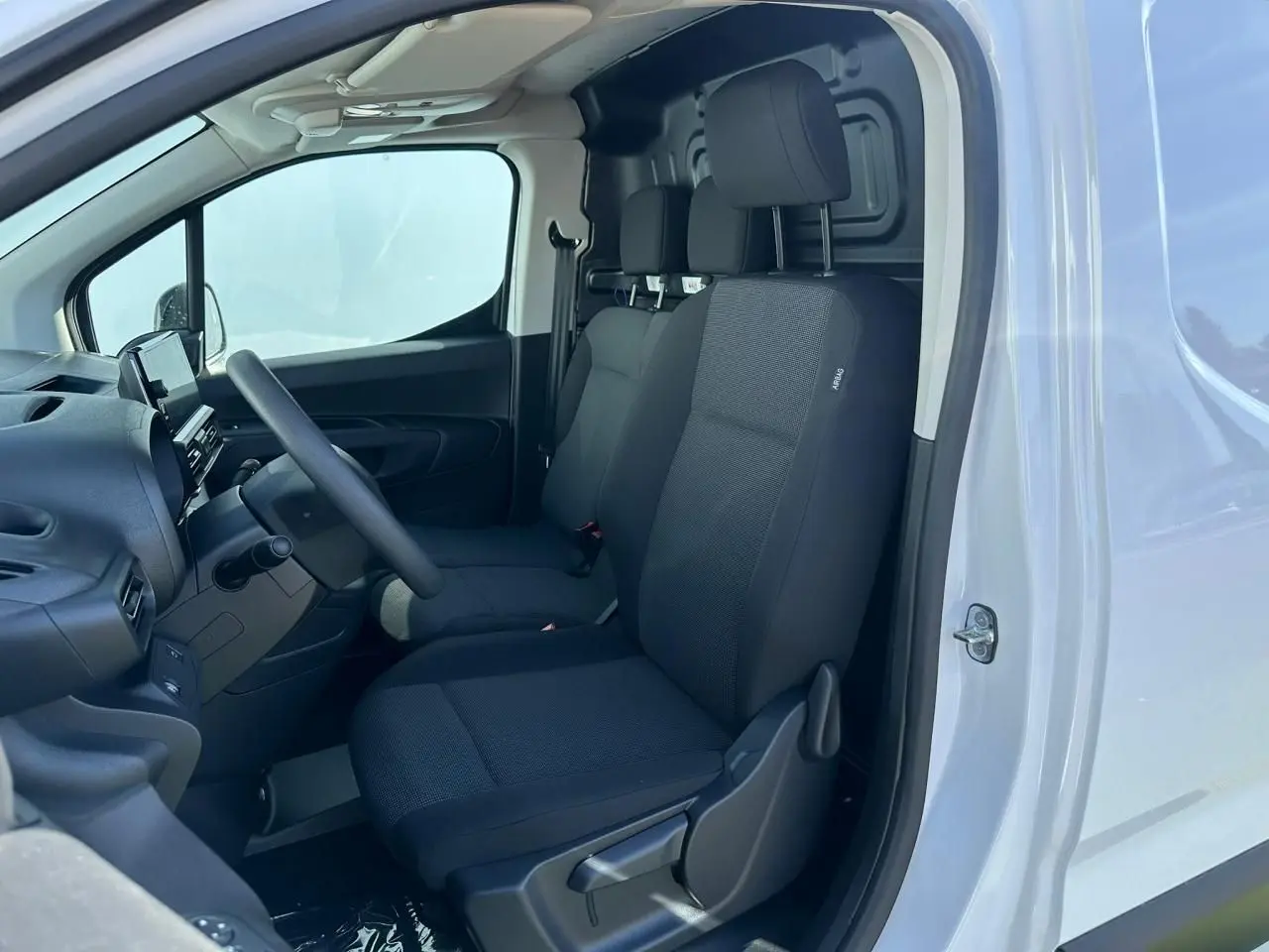 Vue intérieure côté gauche du Citroën Berlingo blanc Icy, montrant les sièges tissu noirs et le tableau de bord.