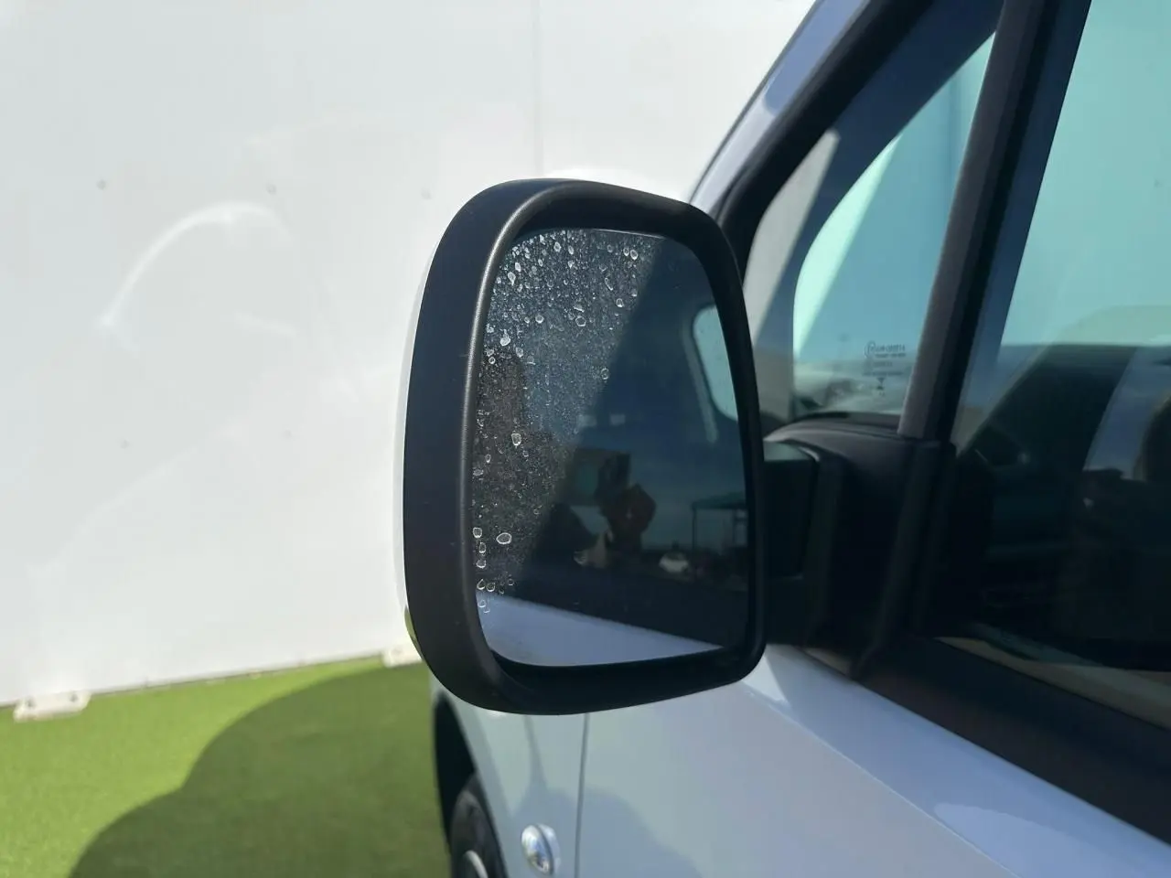 Rétroviseur droit noir brillant du Citroën Berlingo blanc Icy, vue rapprochée sur la portière avant.