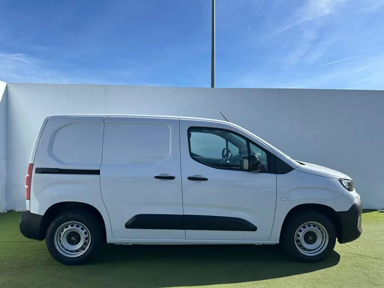 Profil côté gauche d’un utilitaire Citroën Berlingo blanc Icy avec jantes tôles grises et poignées noires.