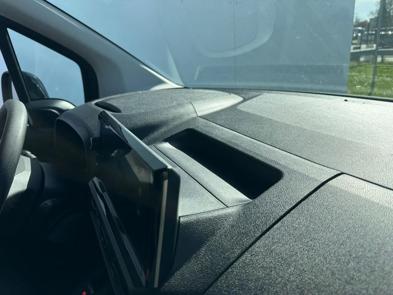 Vue intérieure du tableau de bord noir texturé du Citroën Berlingo III blanc, avec écran tactile déployé côté conducteur.