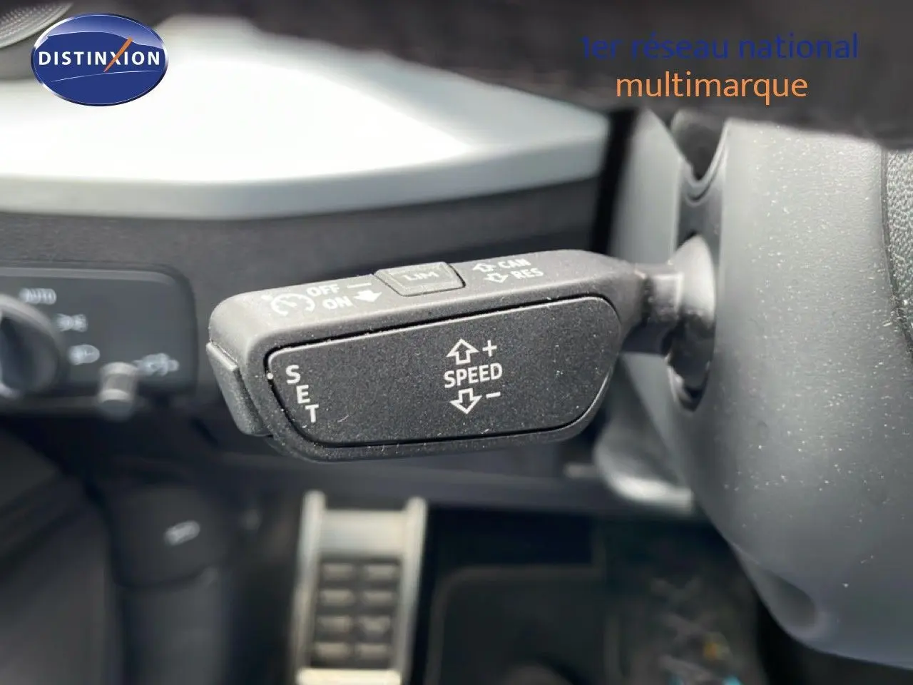 Gros plan sur la commande de régulateur de vitesse au volant d’un Audi Q2 noir mito metal, intérieur noir.