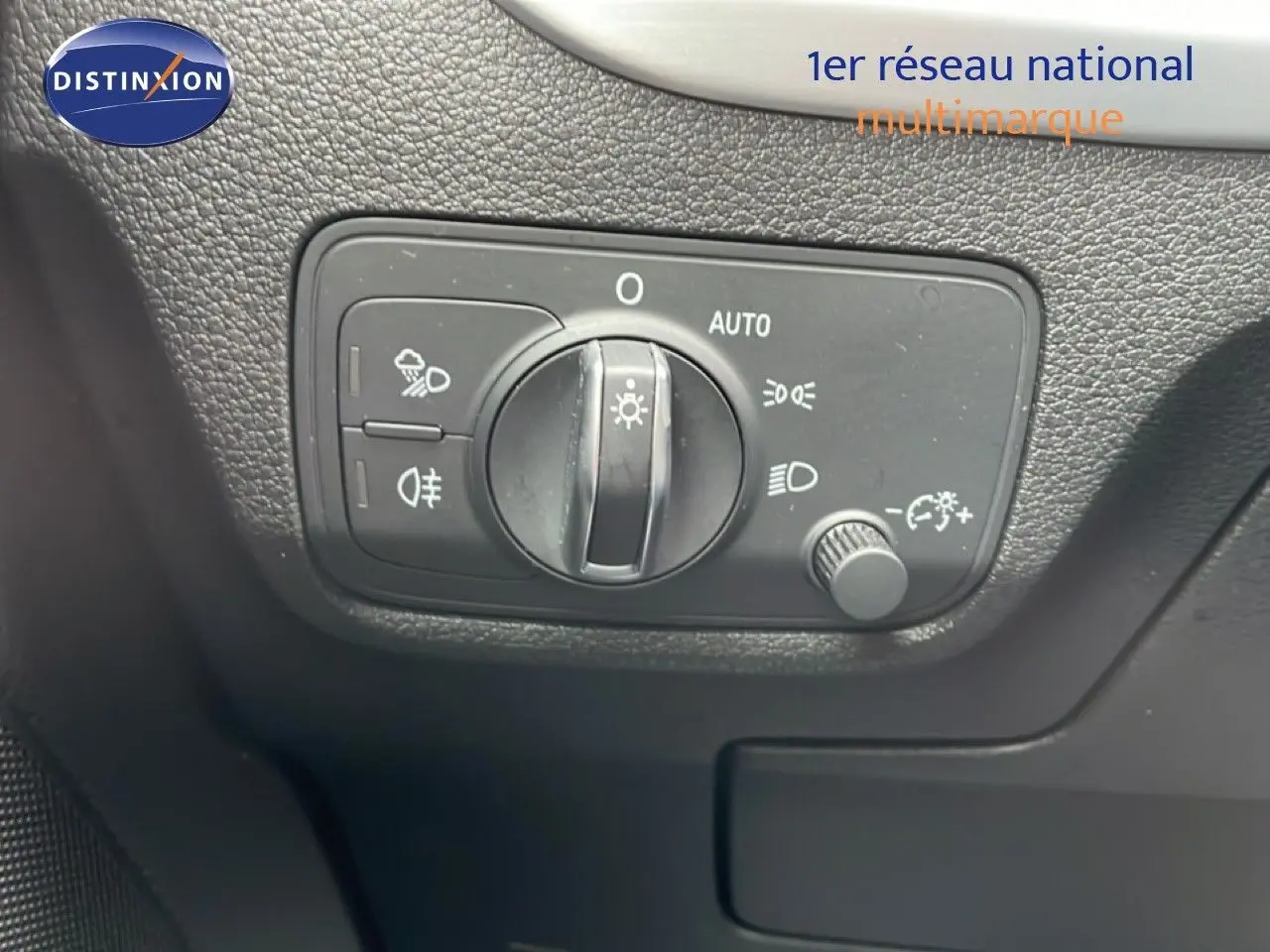 Vue rapprochée du tableau de bord noir de l'Audi Q2 2025 montrant la commande des phares et feux antibrouillard.