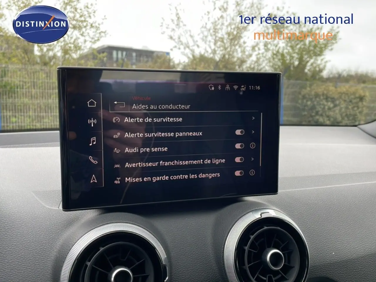 Écran tactile central affichant les aides à la conduite dans l'habitacle d'un Audi Q2 noir, vue intérieure avant.