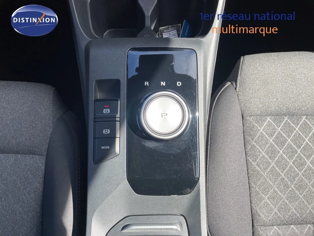 Vue plongeante sur la console centrale du MG3 2024 Pebble Black, mettant en valeur la molette de boîte auto et les sièges tissu gris.