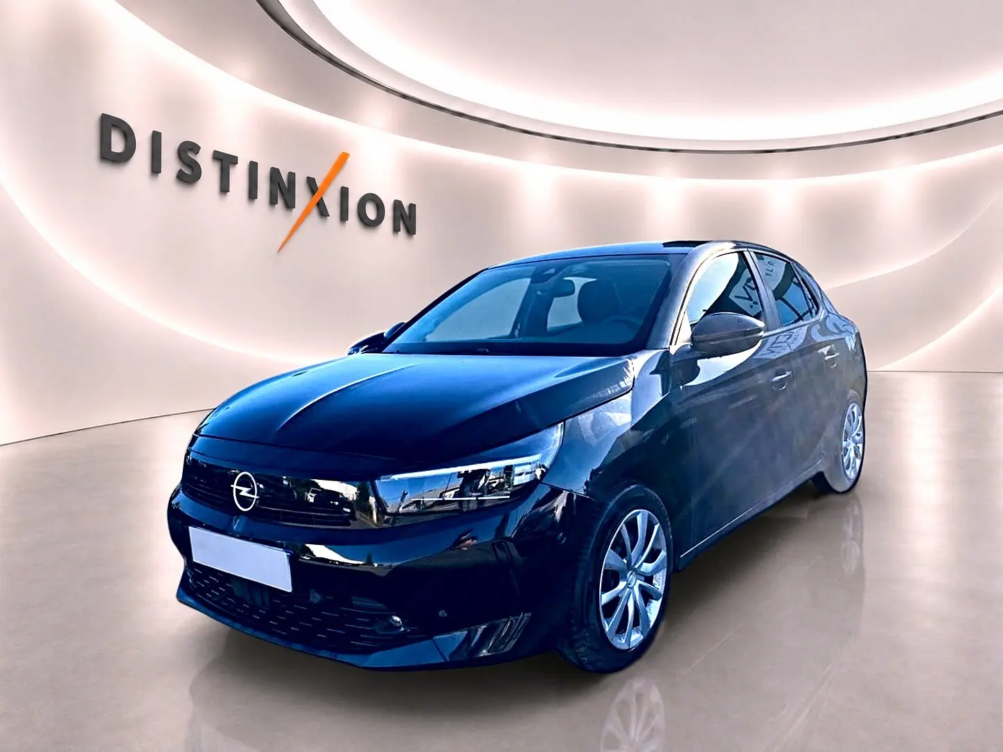 Opel Corsa noire vue en 3/4 avant droit dans un showroom lumineux avec logo Distinxion en arrière-plan.