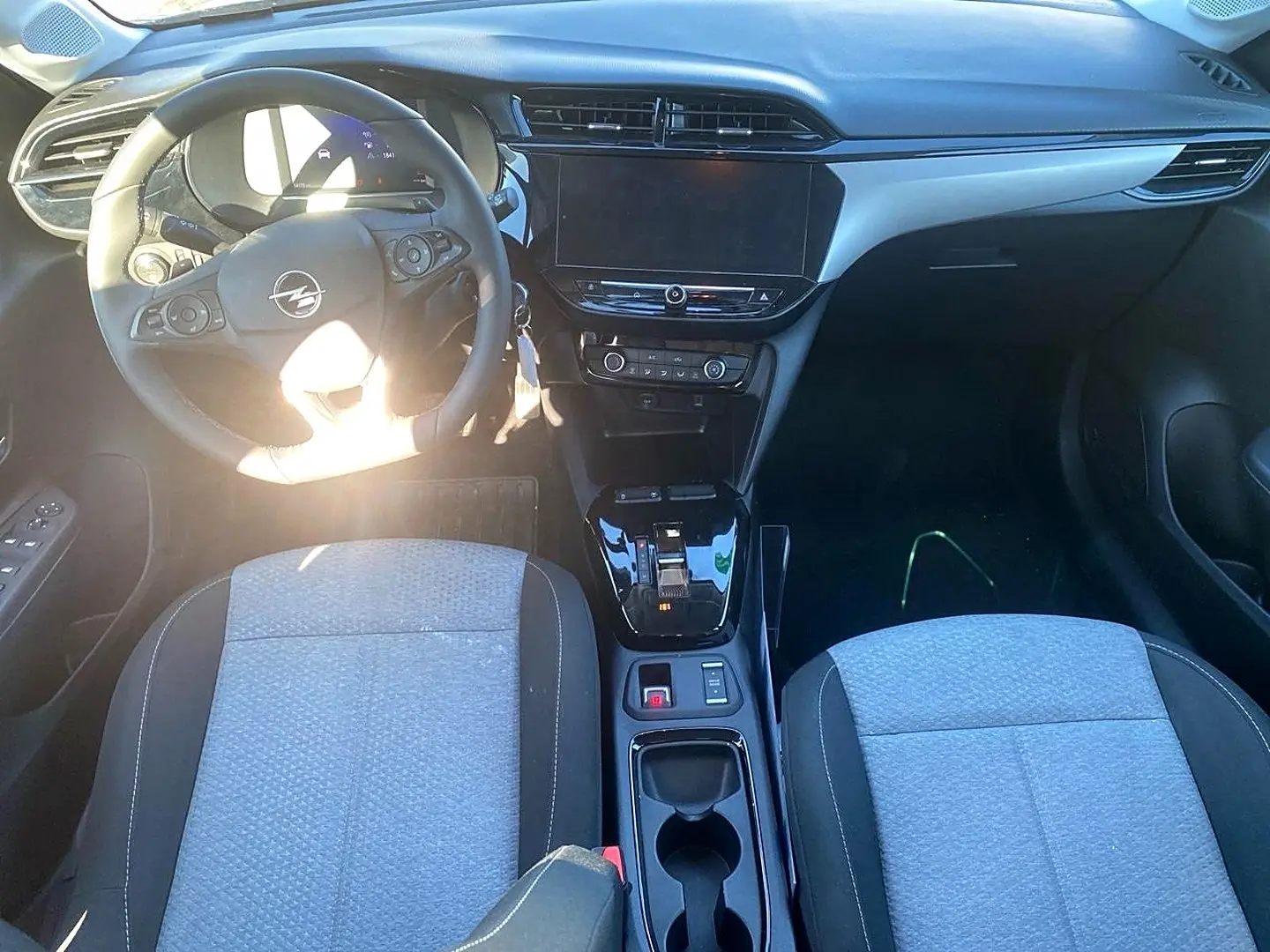 Vue intérieure avant de l’Opel Corsa 1.2 turbo 2025, tableau de bord noir avec écran tactile et sièges tissu gris.