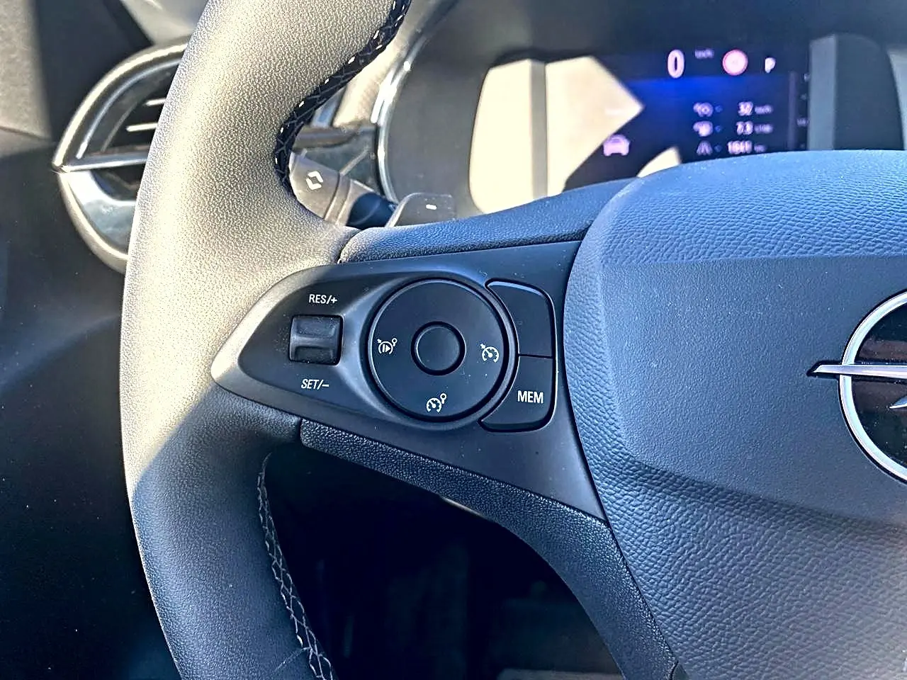 Gros plan sur le côté gauche du volant noir de l'Opel Corsa 2025 avec commandes de régulateur de vitesse.