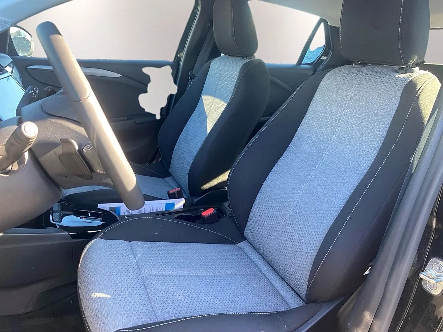 Vue intérieure côté conducteur de l’Opel Corsa noir 2025, sièges tissu bicolore gris et noir avec volant multifonction.