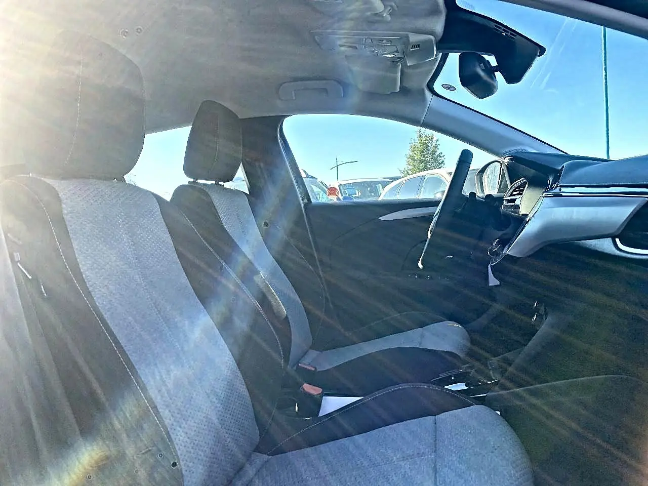 Vue intérieure côté conducteur de l’Opel Corsa 2025, sièges tissu noir et gris avec volant multifonction sport visible.