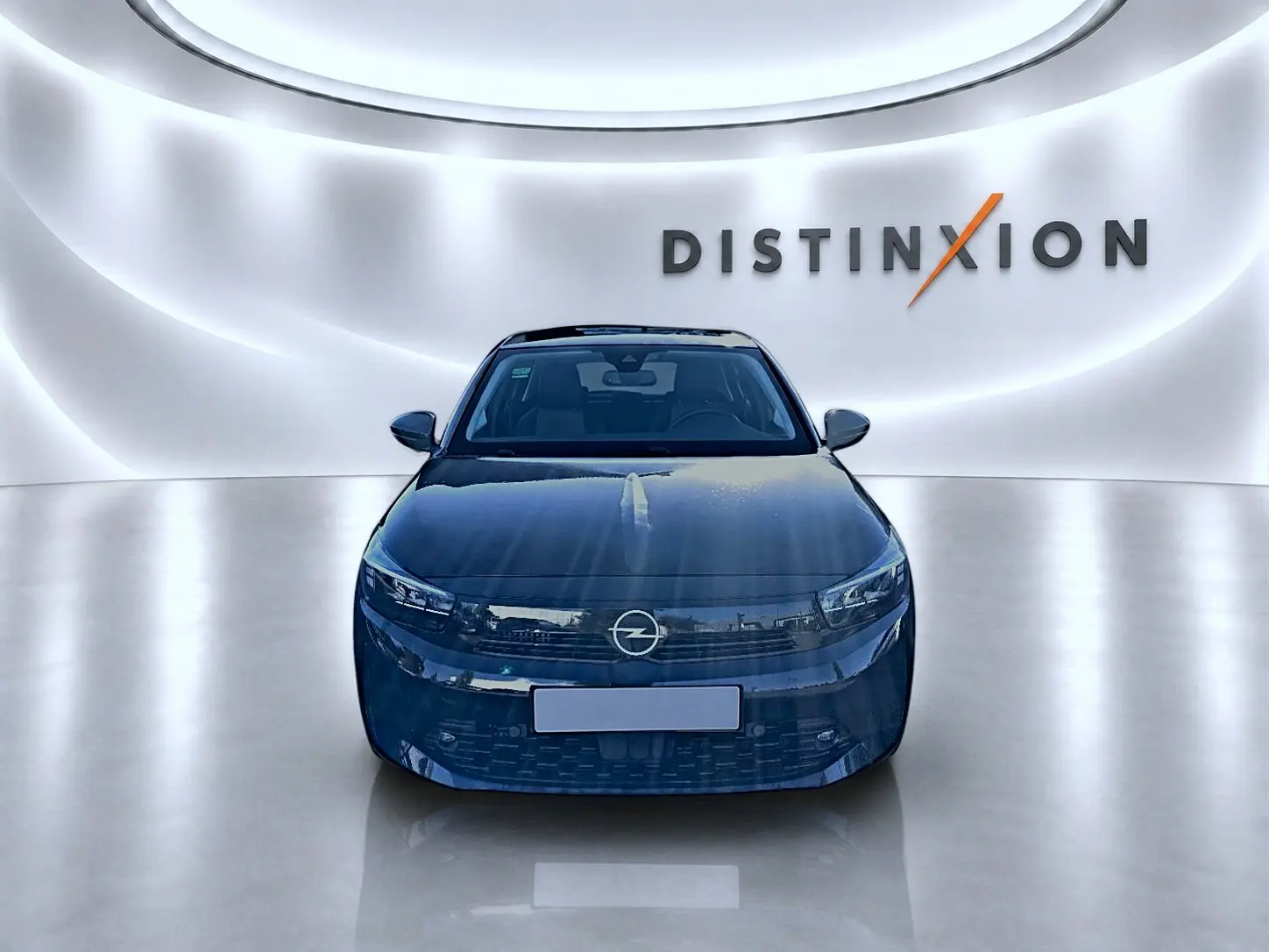 Vue frontale d'une Opel Corsa noire 2025 dans un showroom avec un mur lumineux marqué Distinxion.