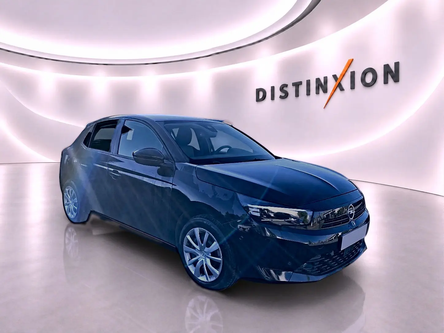 Opel Corsa noire vue 3/4 avant droit dans un showroom lumineux avec logo Distinxion en arrière-plan.
