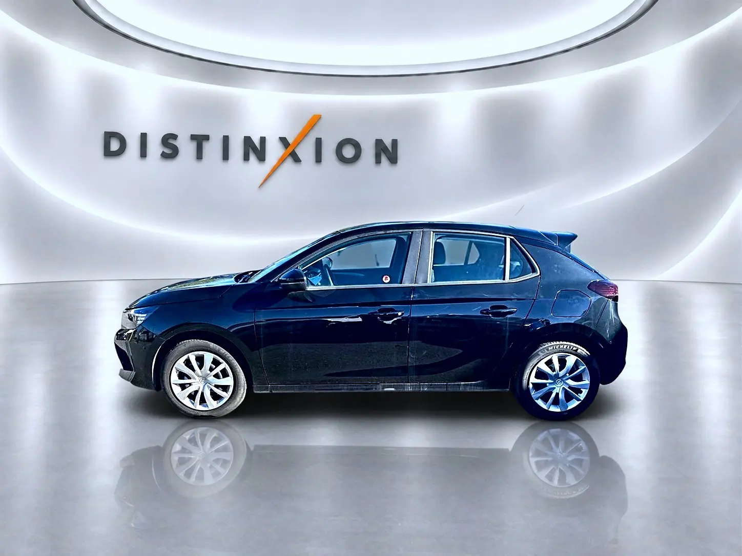 Opel Corsa noire vue de profil côté gauche, avec jantes alliage et becquet arrière en showroom lumineux.