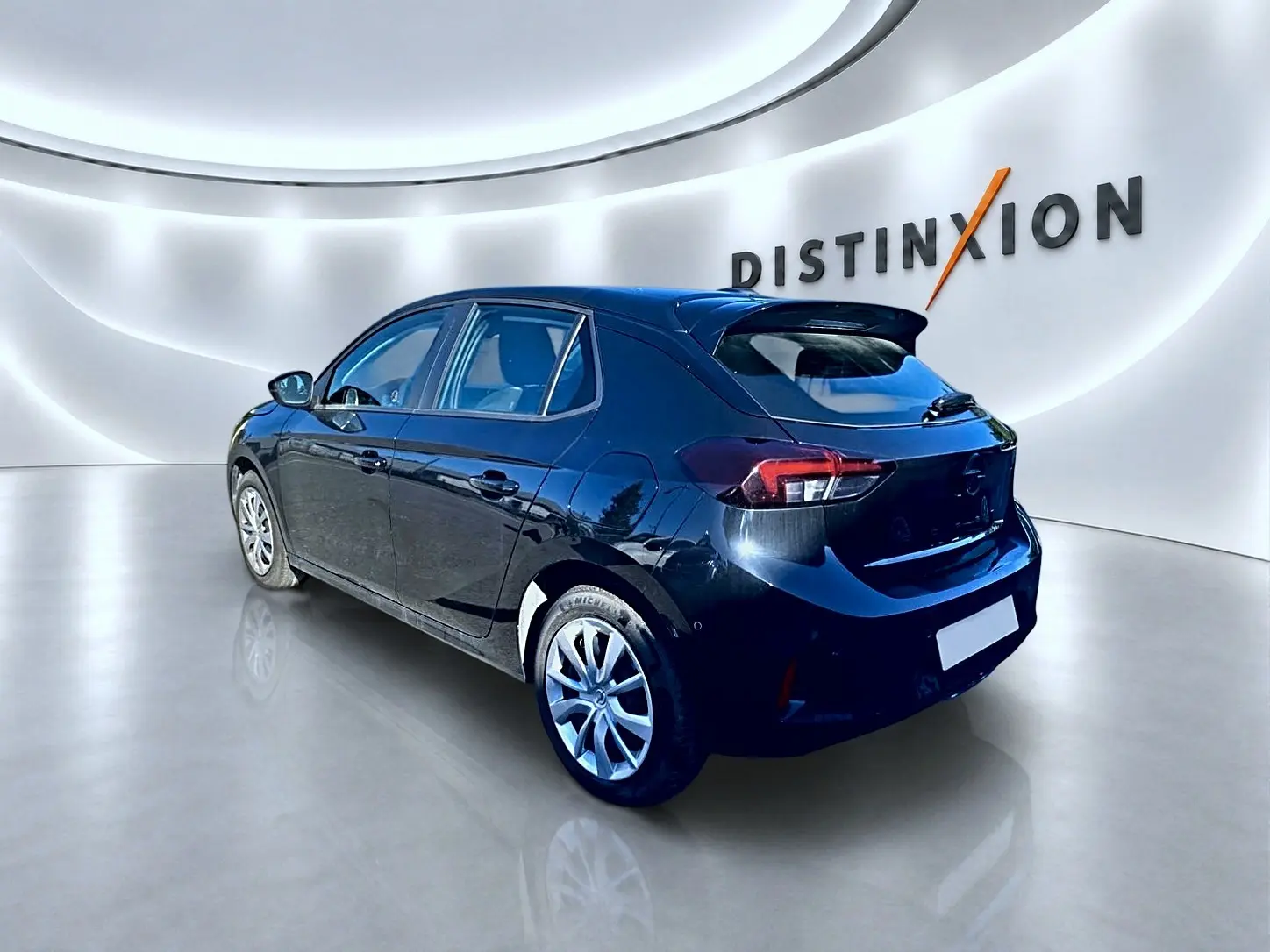 Opel Corsa noire vue 3/4 arrière droit dans un showroom lumineux avec becquet et jantes alliage.