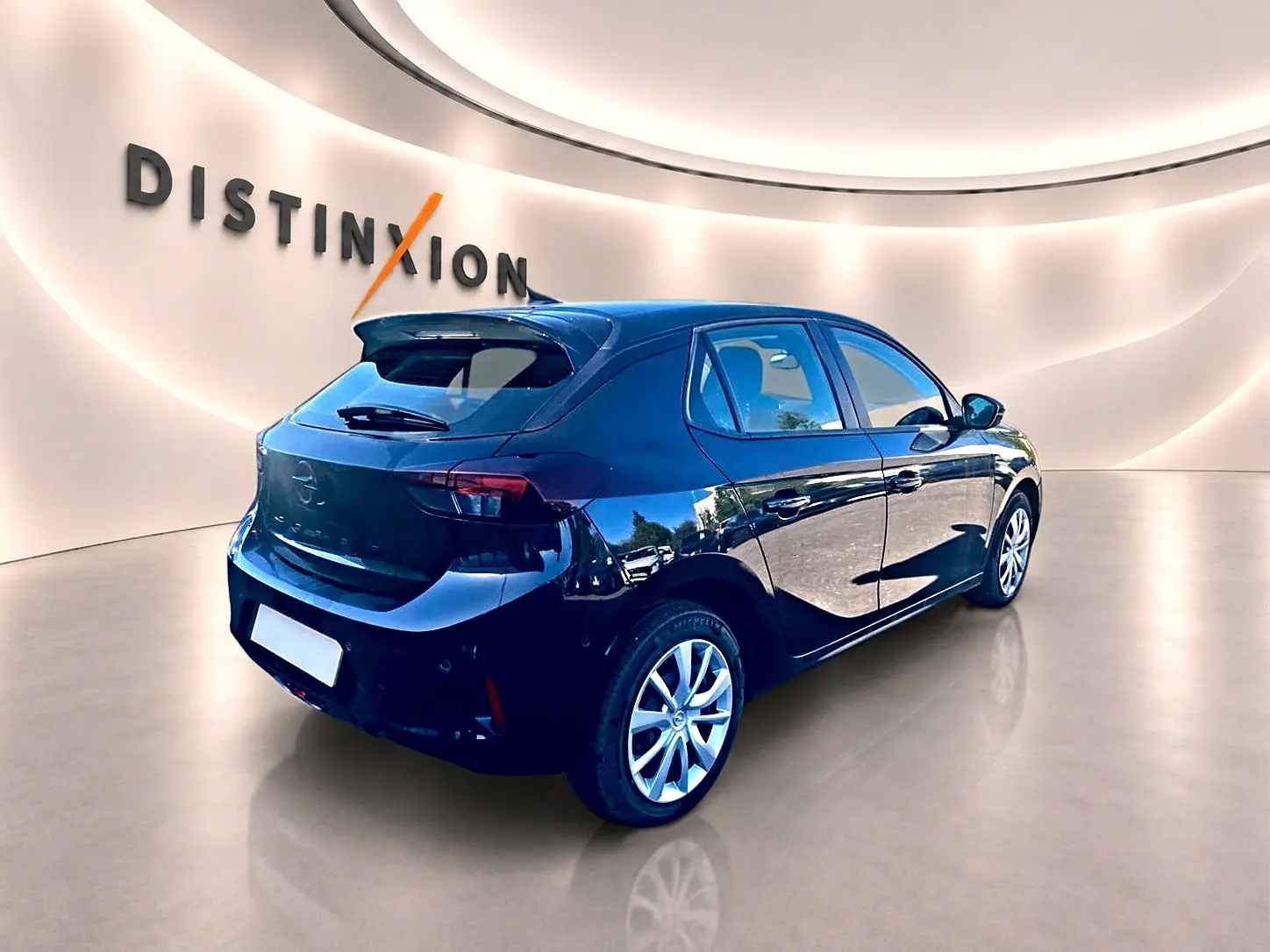 Opel Corsa noire vue 3/4 arrière droit dans un showroom avec becquet et jantes alliage visibles.