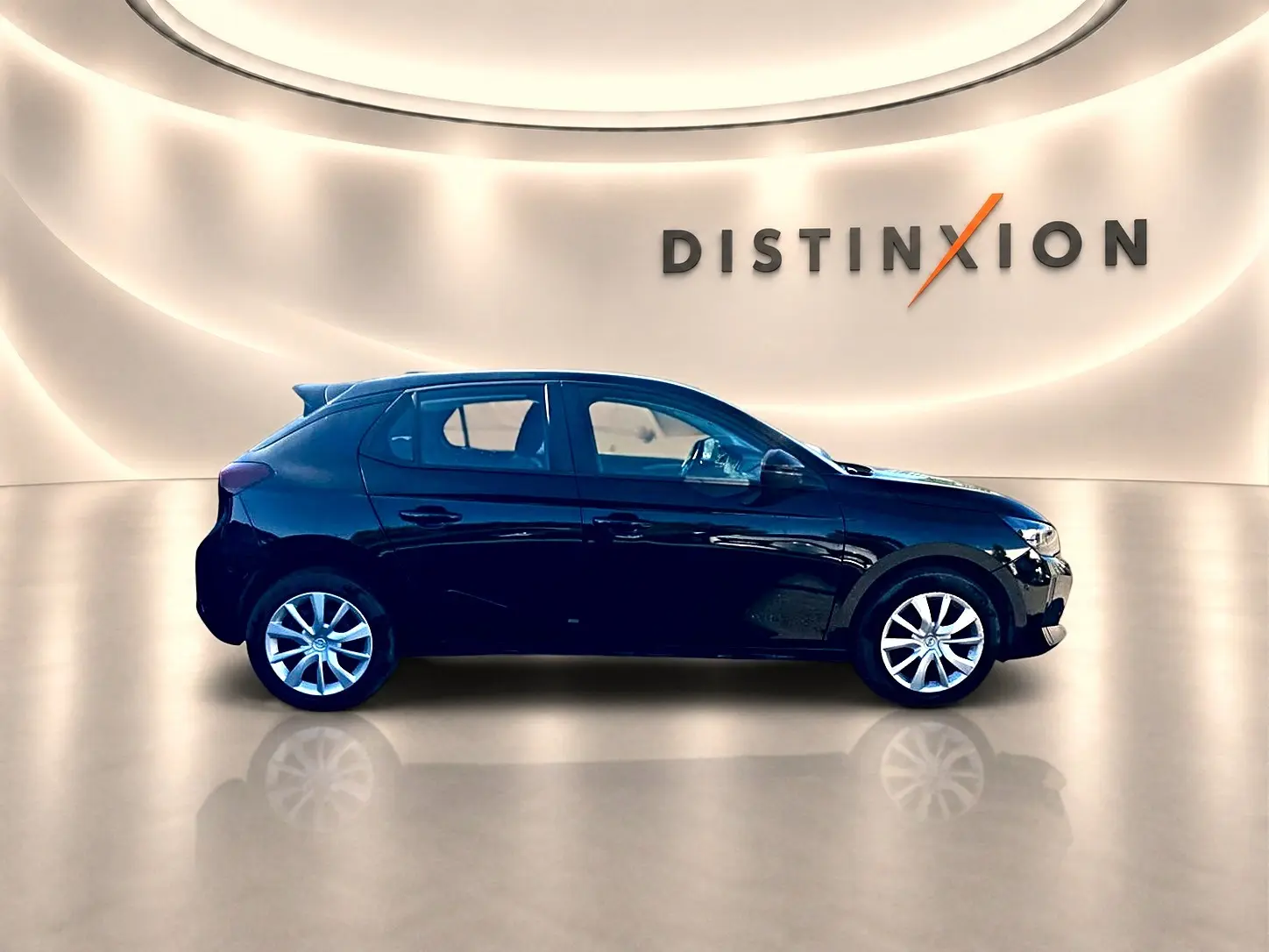 Opel Corsa noire vue de profil côté gauche dans un showroom lumineux avec logo Distinxion en arrière-plan.