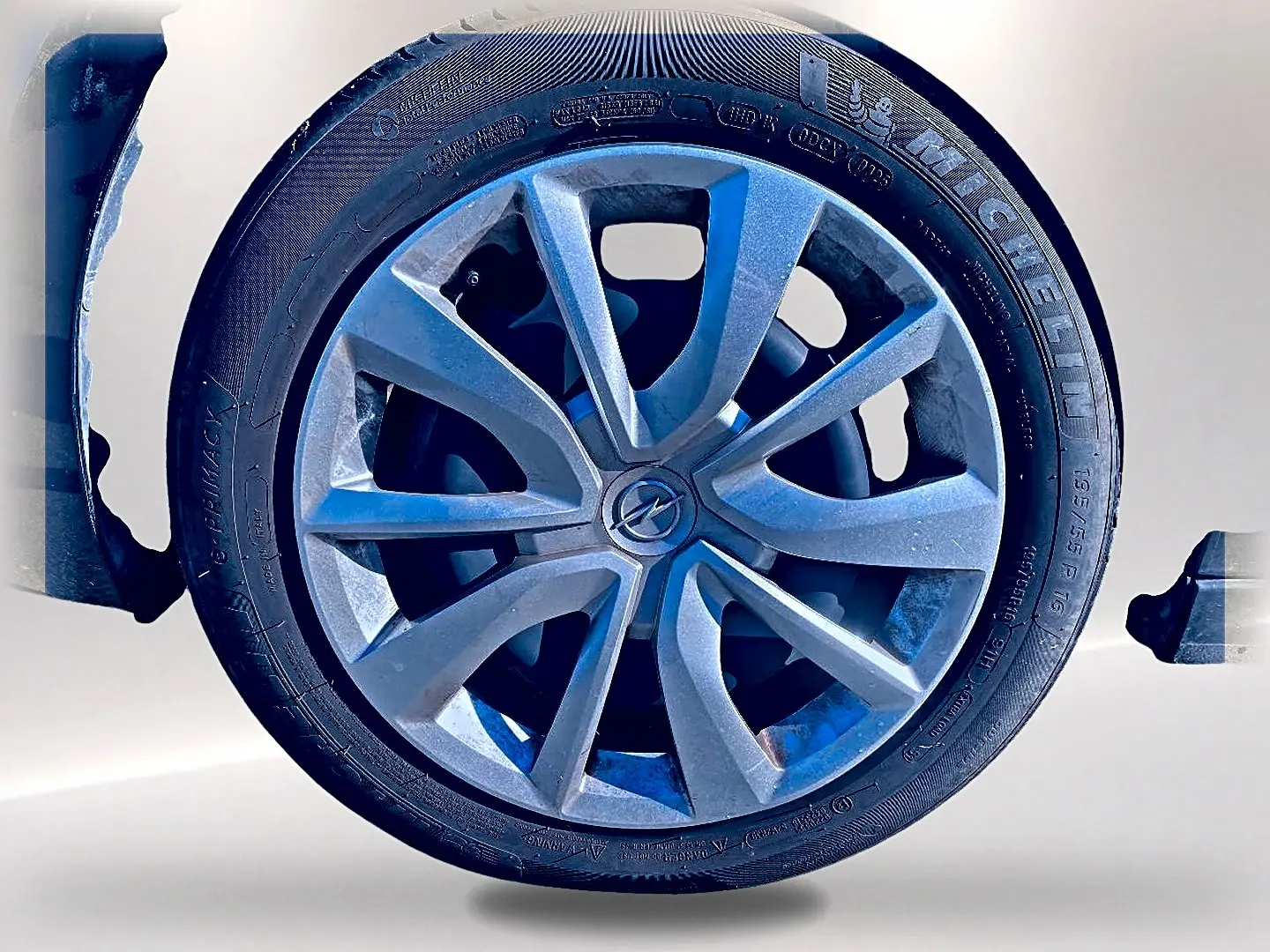 Gros plan sur la roue avant gauche de l’Opel Corsa noire, mettant en valeur la jante alu et le logo Opel central.