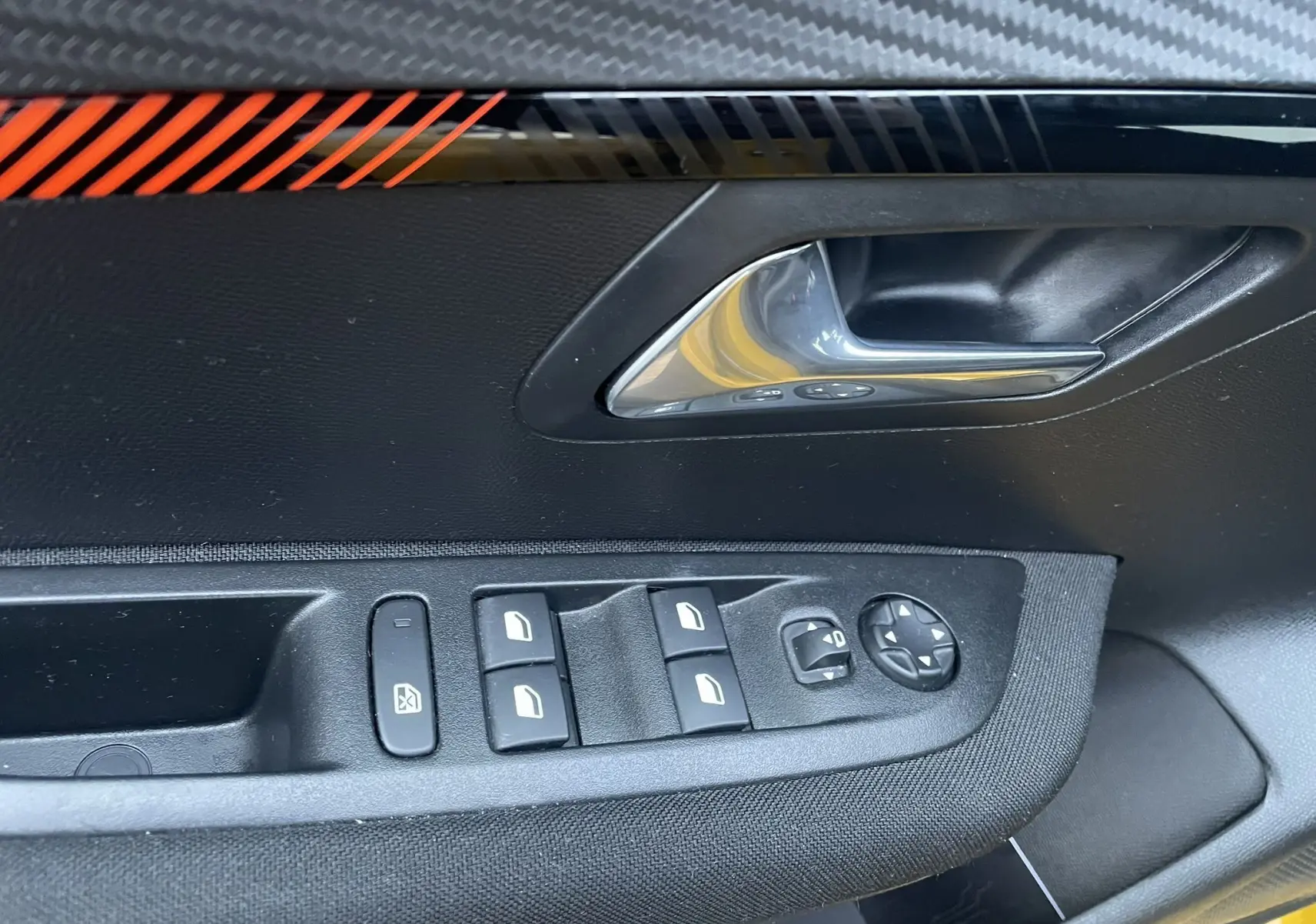 Poignée de porte côté gauche avec commandes des vitres et rétroviseurs dans une Peugeot 208 électrique jaune 2023.