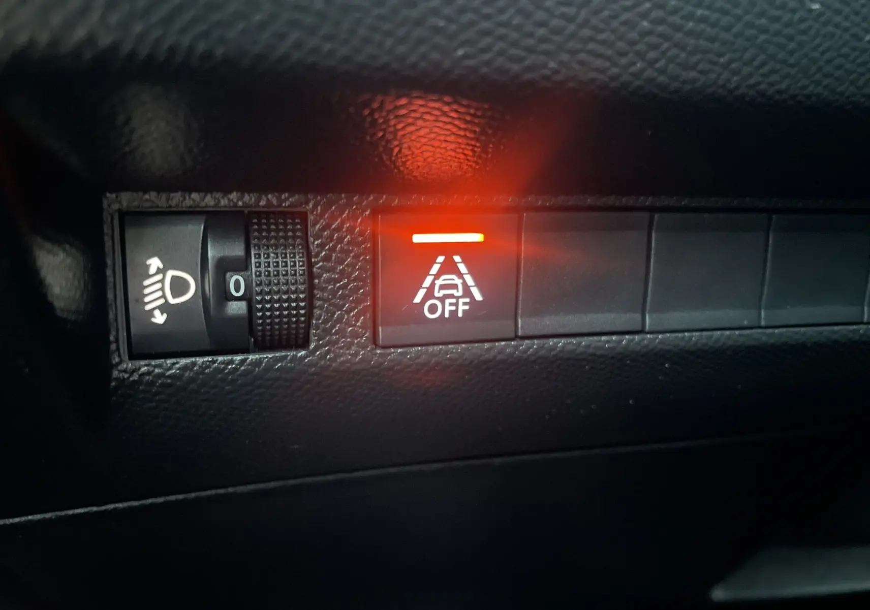 Gros plan sur le tableau de bord du Peugeot 208 II électrique 2023, bouton d'alerte de maintien de voie allumé en rouge.