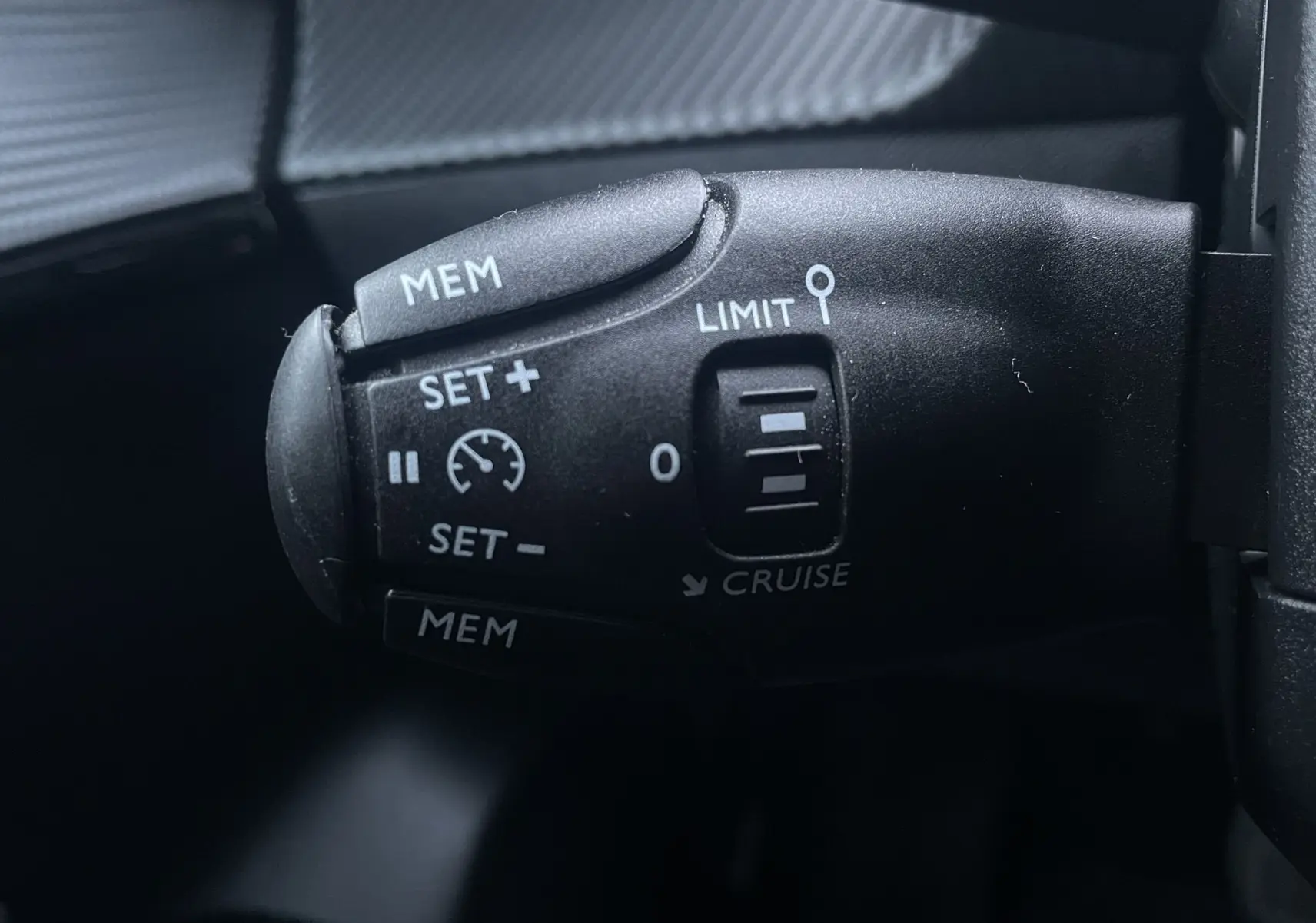 Gros plan sur la commande de régulateur de vitesse noire dans l'habitacle d'une Peugeot 208 électrique jaune 2023.