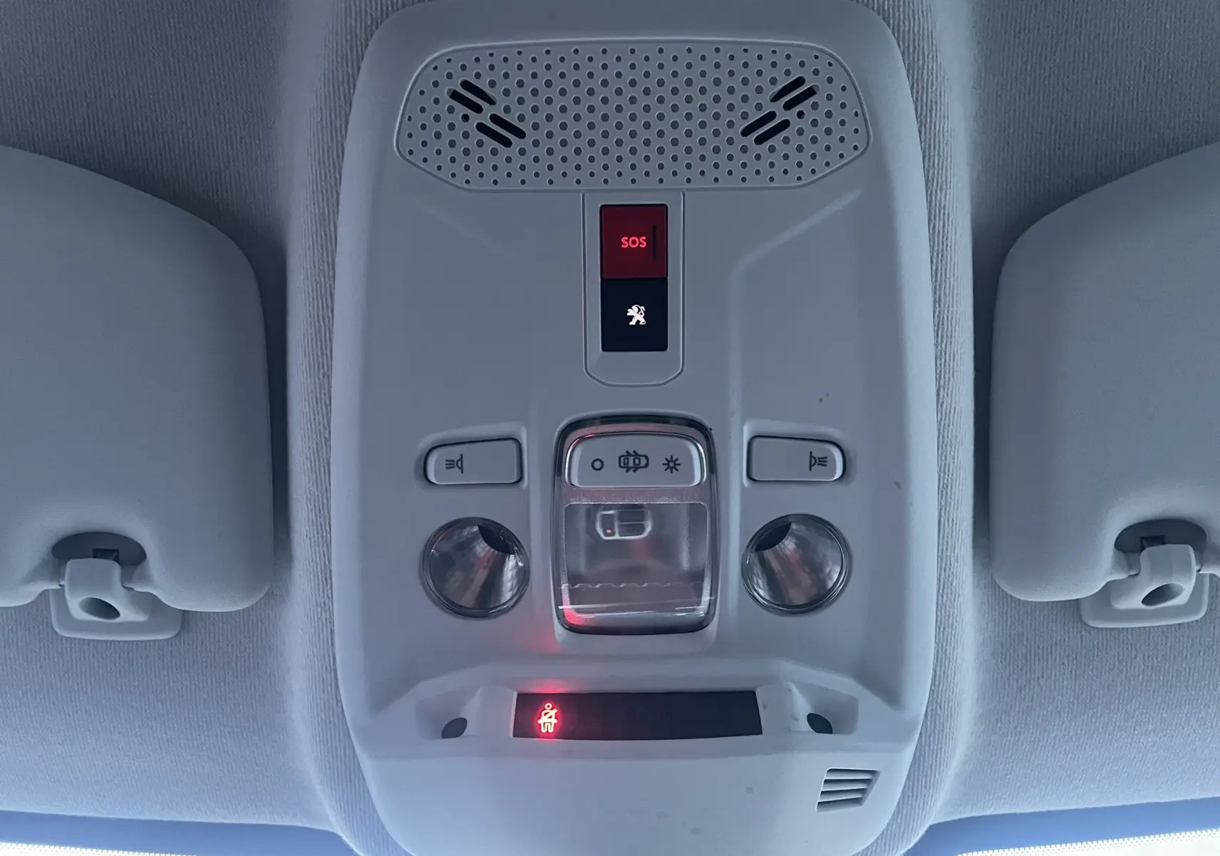 Plafonnier intérieur gris avec boutons SOS et éclairage, vu de dessous dans une Peugeot 208 électrique jaune 2023.