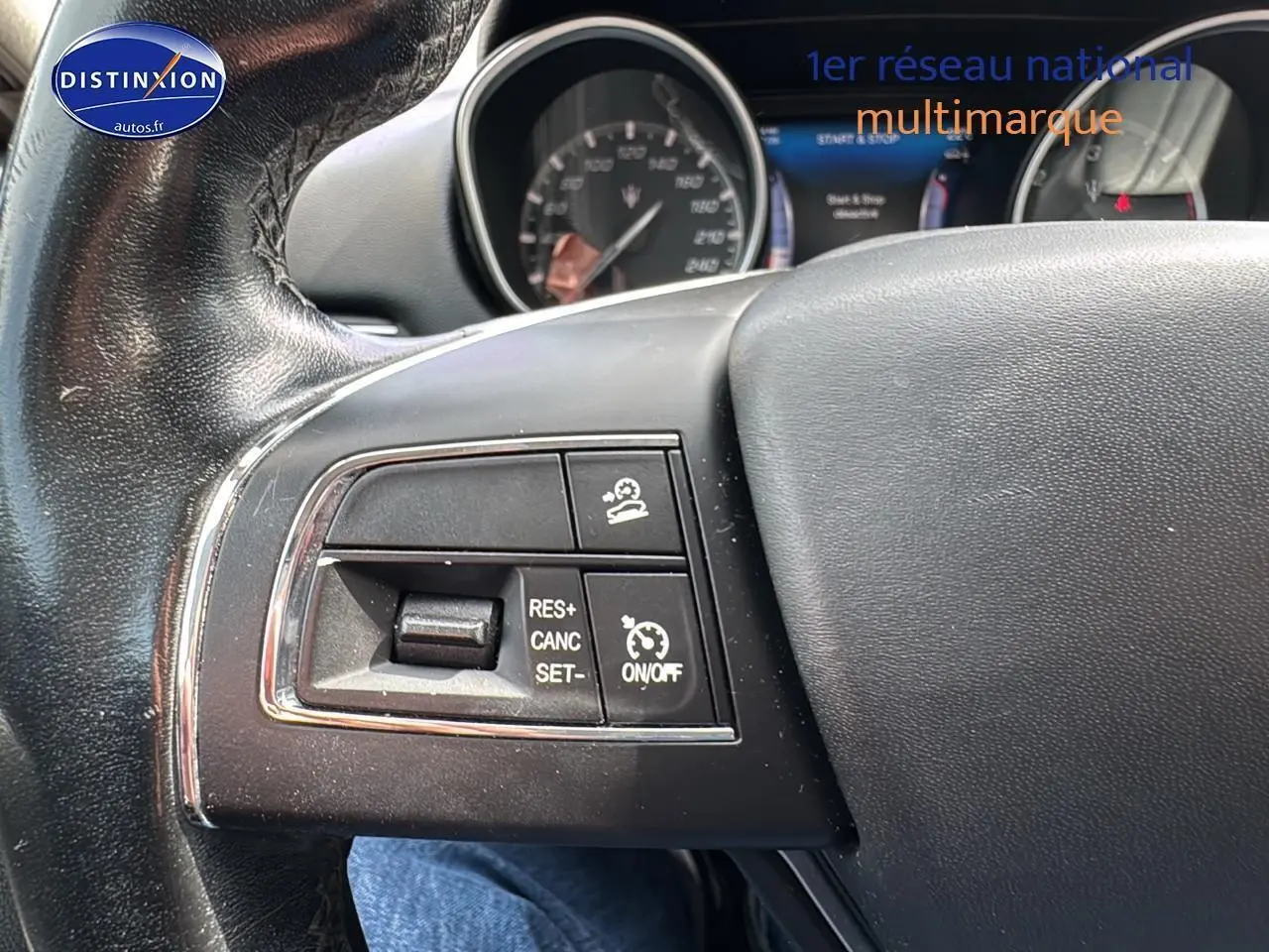 Gros plan sur les commandes de régulateur de vitesse au volant cuir noir d'une Maserati Levante gris 2017.