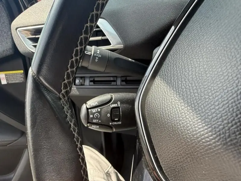 Gros plan sur le volant noir et les commandes de régulateur de vitesse du Peugeot 3008 2018 côté conducteur.