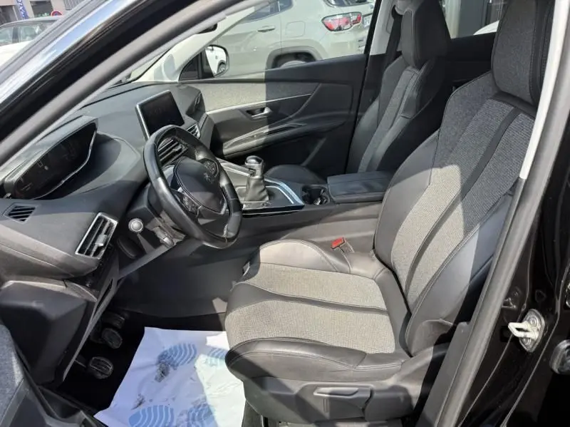 Vue intérieure côté conducteur du Peugeot 3008 noir 2018, montrant sièges tissu et cuir, volant et levier de vitesse manuel.