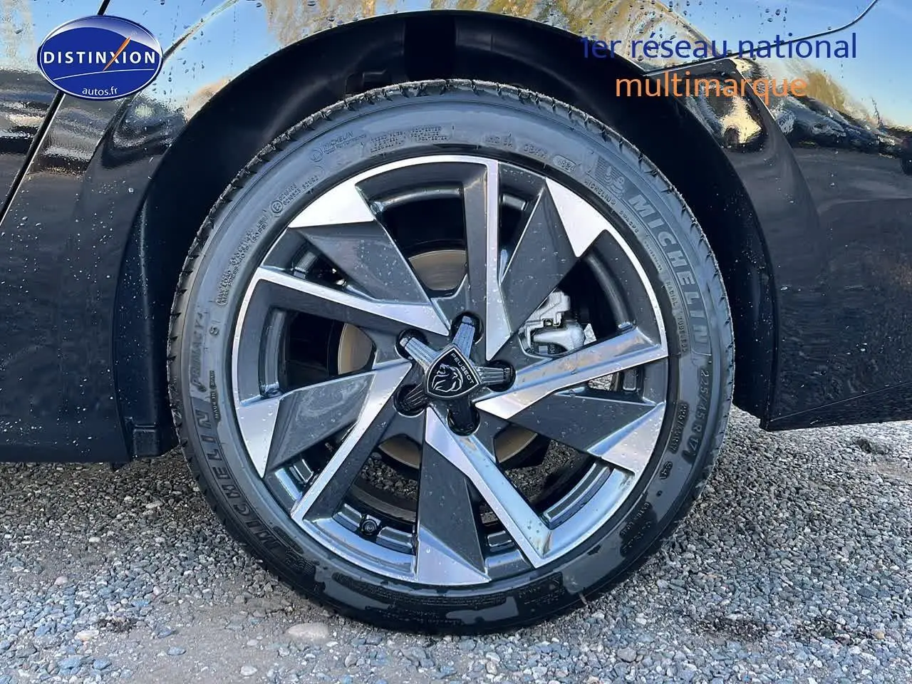 Gros plan sur la jante alu avant droite de la Peugeot 308 SW noire perle avec logo lion central visible.