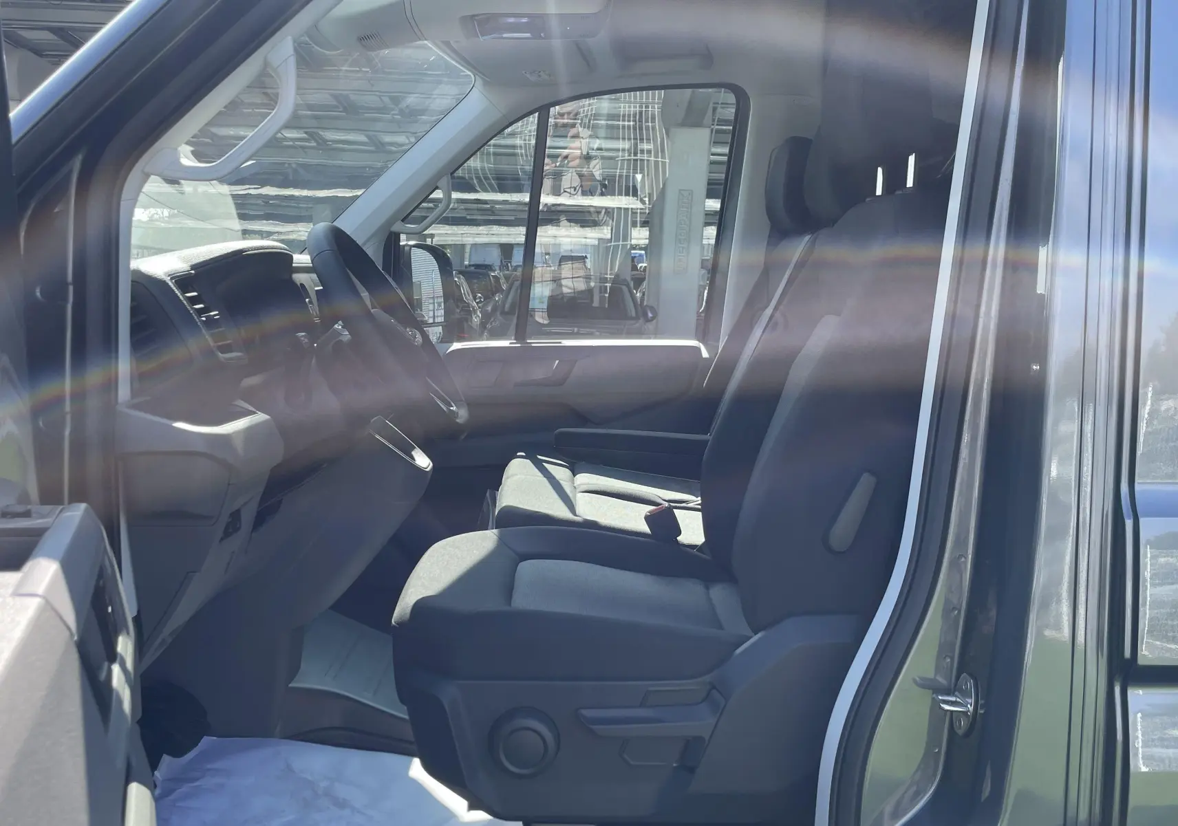 Vue intérieure côté conducteur du Volkswagen Crafter gris Indium 2025, montrant sièges et tableau de bord.