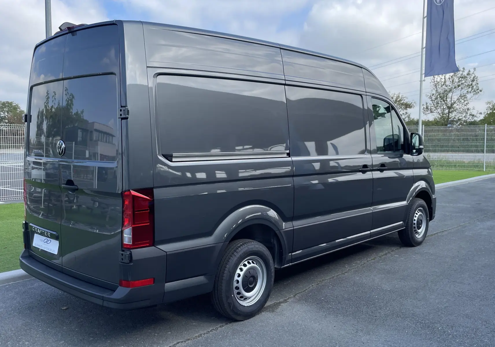 Vue 3/4 arrière droite d'un Volkswagen Crafter Van gris Indium avec vitres arrière opaques sur parking extérieur.