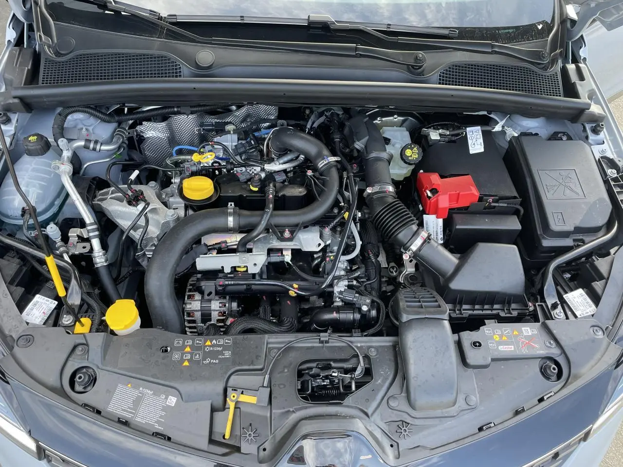 Vue plongeante sur le moteur essence d'une Renault Clio Gris Rafale avec détails des composants sous le capot.