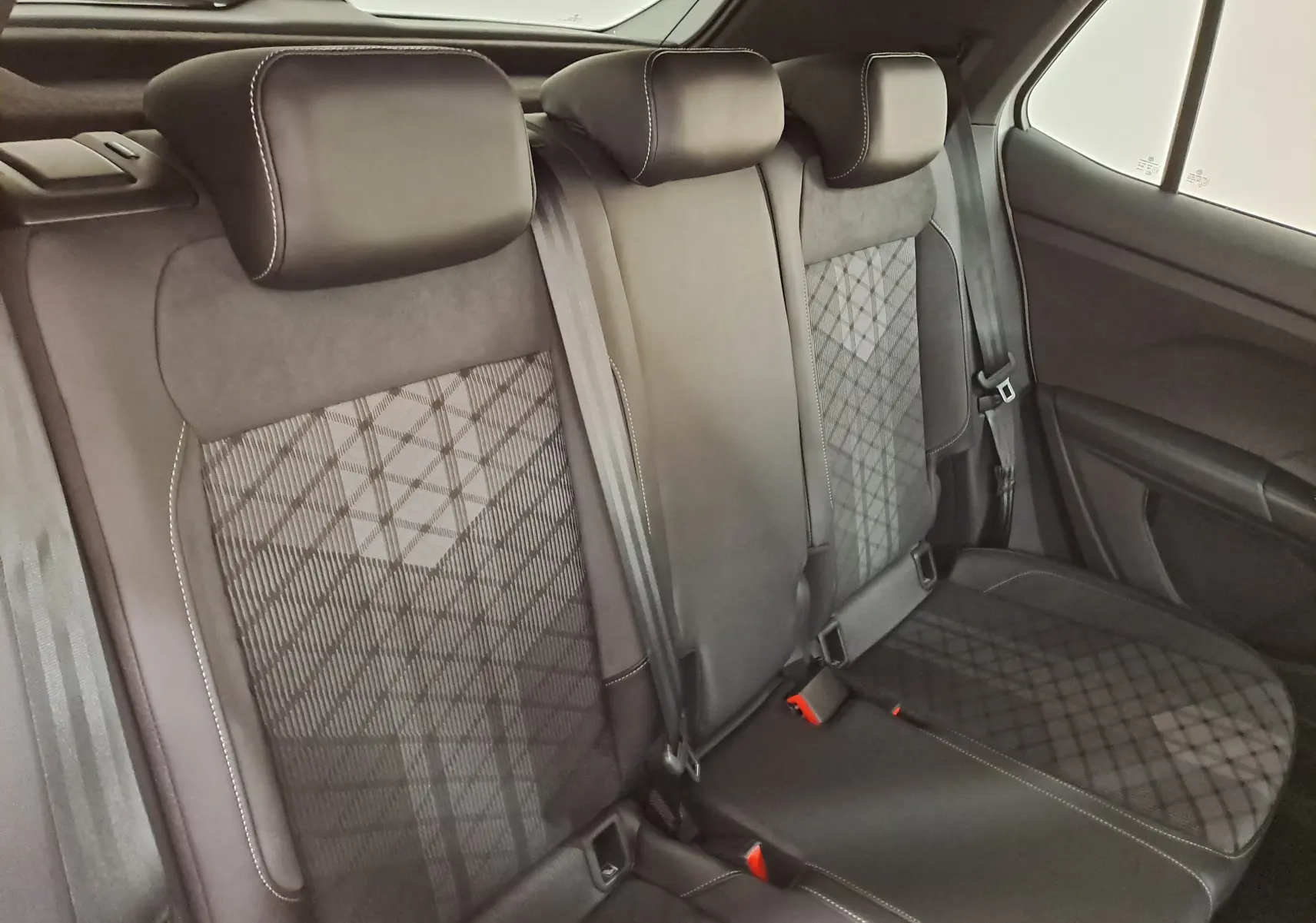 Vue intérieure des sièges arrière noirs avec surpiqûres blanches du Volkswagen T-Cross 1.0 TSI R-Line Edition 2025.