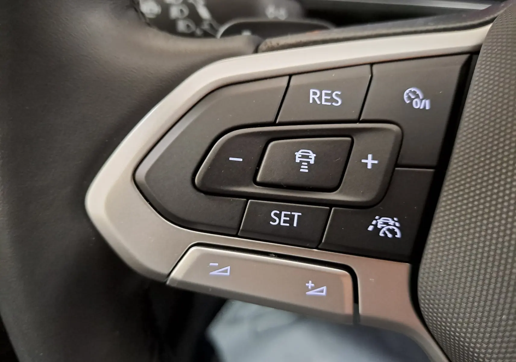 Gros plan sur les commandes de régulateur de vitesse au volant du Volkswagen T-Cross 2025 blanc pur R-Line Edition.