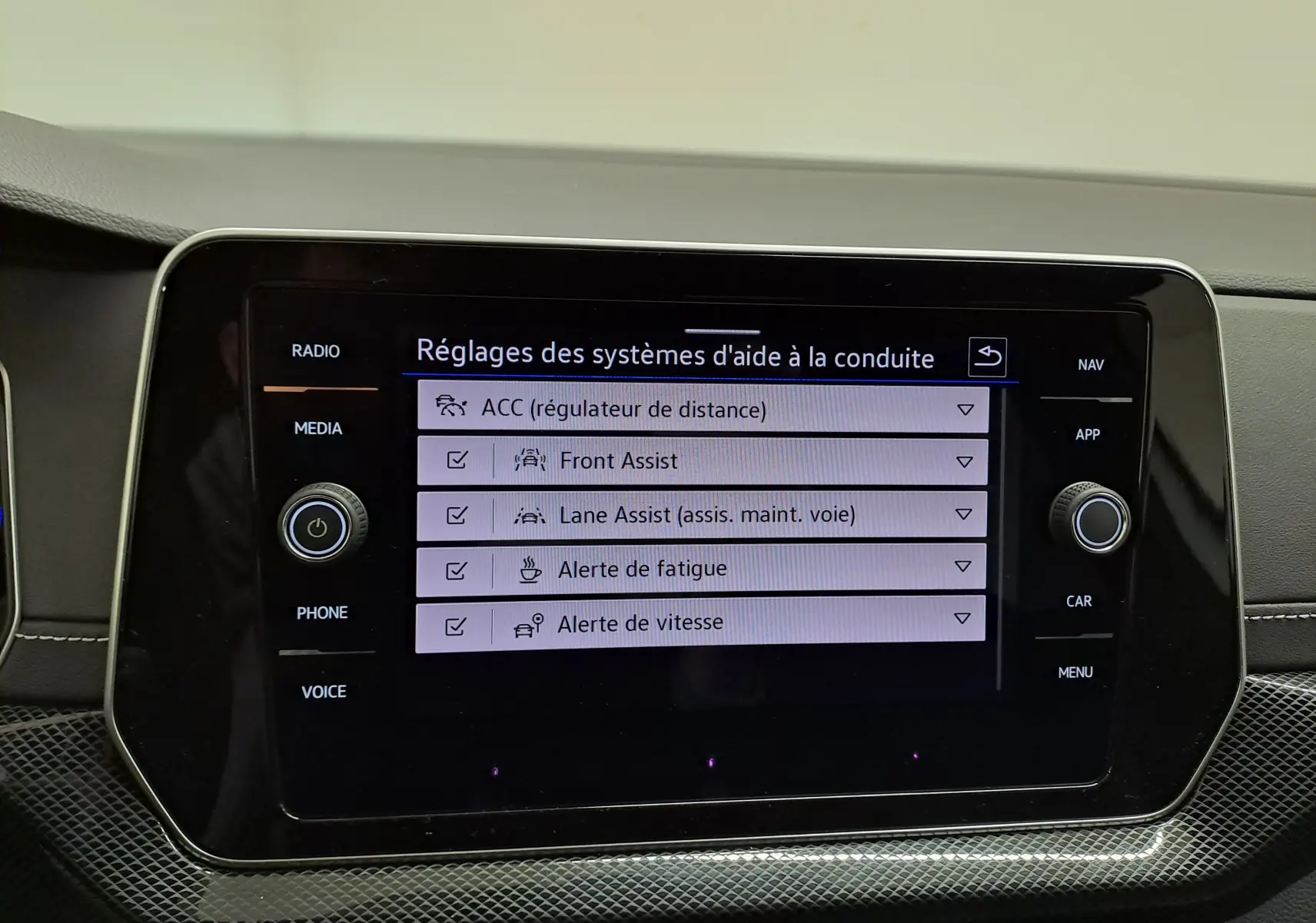 Écran tactile central du Volkswagen T-Cross 2025 blanc, affichant les réglages des aides à la conduite.